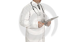 Male doctor standing in front of white background, wearing a mask and a white coat holding a tablet computer