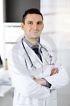 Male doctor standing straight in sunny clinic. Perfect medical service in hospital