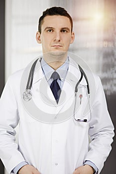 Male doctor standing straight in sunny clinic. Perfect medical service in hospital