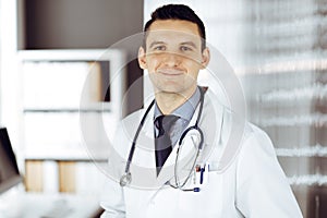 Male doctor standing straight in sunny clinic. Perfect medical service in hospital