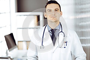 Male doctor standing straight in sunny clinic. Perfect medical service in hospital