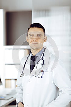 Male doctor standing straight in sunny clinic. Perfect medical service in hospital