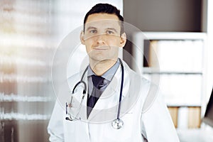 Male doctor standing straight in sunny clinic. Perfect medical service in hospital