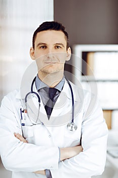 Male doctor standing straight in sunny clinic. Perfect medical service in hospital