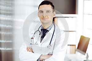 Male doctor standing straight in sunny clinic. Perfect medical service in hospital