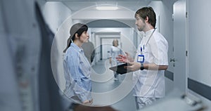 Male doctor stands in clinic corridor with female patient