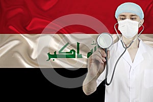 Male doctor with a stethoscope on the background of the silk national flag of Iraq, the concept of national medical care, health,
