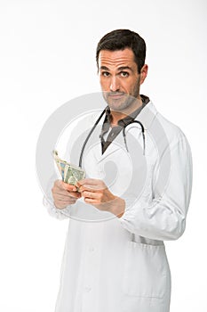 Male doctor with stethoscope while counting money