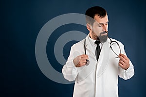 Male doctor with stethoscope in medical uniform arranges his stethoscope