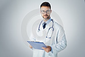 Male doctor studio portrait while standing at isolated bakcground