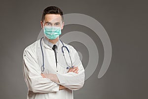 Male doctor in surgical mask with arms crossed photo