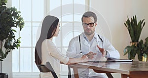 Male doctor talk to young woman patient at medical consultation