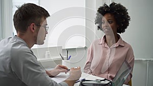 Male doctor talking to female patient and sitting at table during health check in clinic spbd.