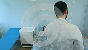 Male doctor talking to female patients on drip resting in hospital ward