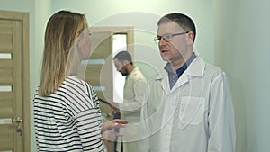 Male doctor talking to young woman patient in the hospital hall