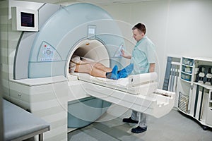 Male doctor turns on magnetic resonance imaging machine with patient inside