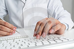 Male doctor typing at wireless computer keyboard