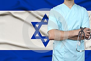 Male doctor in uniform professional clothes with a stethoscope stands against the background of the national flag, the concept of