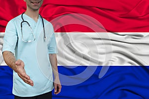 Male doctor in uniform professional clothes with a stethoscope stands against the background of the national flag, the concept of