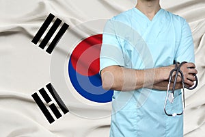 Male doctor in uniform professional clothes with a stethoscope stands against the background of the national flag, the concept of