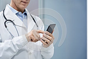 Male doctor using smart phone mobile e health technology, copy space.