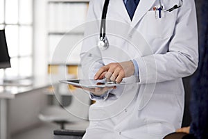 Male doctor using tablet computer in clinic, close-up. Perfect medical service in hospital. Medicine and healthcare