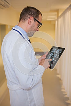 Male doctor using a tablet computer. In a hospital corridor.