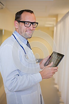 Male doctor using a tablet computer. In a hospital corridor.