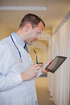 Male doctor using a tablet computer. In a hospital corridor.