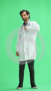 male doctor in a white coat on a green background smiling in full length