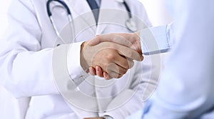 Male doctor and woman patient shaking hands. Partnership in medicine, trust and medical ethics concept