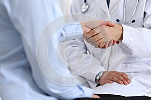 Male doctor and woman patient shaking hands. Partnership in medicine, trust and medical ethics concept