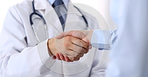 Male doctor and woman patient shaking hands. Partnership in medicine, trust and medical ethics concept