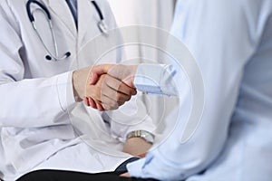 Male doctor and woman patient shaking hands. Partnership in medicine, trust and medical ethics concept