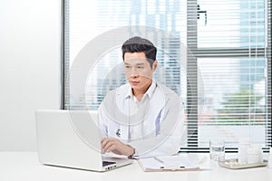 Male doctor working at desk in doctor`s room