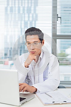 Male doctor working at desk in doctor`s room