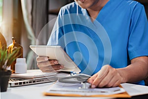 Male doctor working on desk with laptop computer and paperwork in the office.