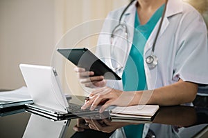 Male doctor working on desk with laptop computer and paperwork in the office.