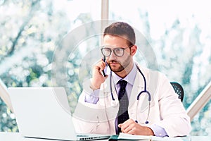 Male doctor working at desk in doctor`s office photo