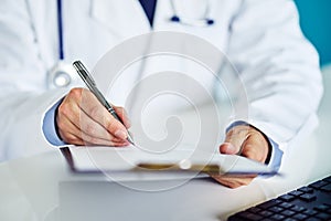 Male doctor writes notes on the clipboard photo