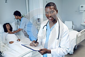 Male doctor writing on clipboard in the ward at hospital