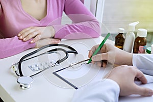 Male doctor writing patient notes on a medical examination or prescription