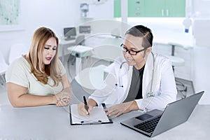 Male doctor writing a prescription to his patient