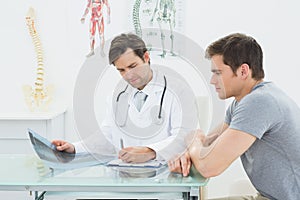 Male doctor writing reports besides patient