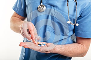 Male doctors pouring pills froma a bottle on his palm