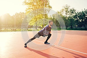 Male doing stretching exercise, preparing for morning workout in the park