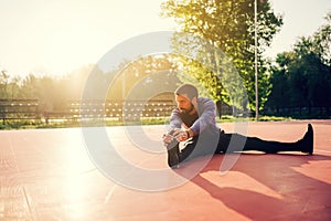 Male doing stretching exercise, preparing for morning workout in the park