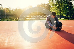 Male doing stretching exercise, preparing for morning workout in the park