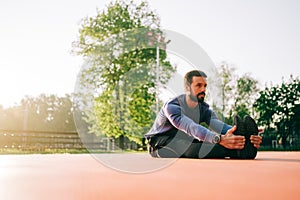 Male doing stretching exercise, preparing for morning workout in the park