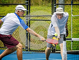 Male doubles teammates both attack the ball during a pickleball tournament